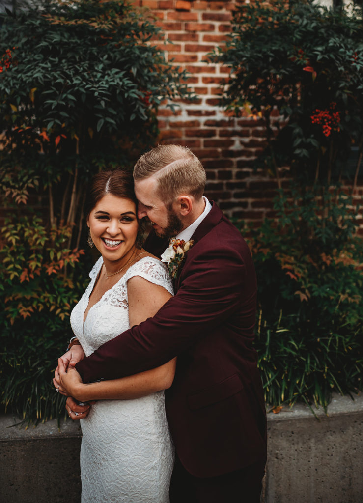 groom standing behind his bride and holding her around the hips and leaning into her ear to whisper to her captured by Baltimore wedding photographers