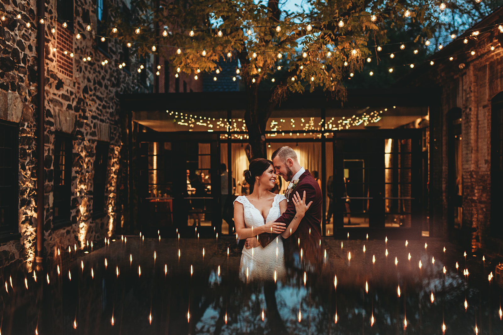 Baltimore wedding photographers captures bride and groom embracing under outdoor twinkle lights right after the sunsets for their Baltimore wedding