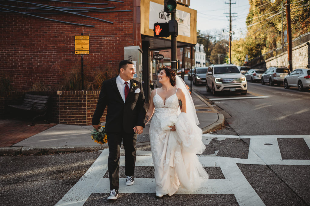 Baltimore wedding pictures with bride and groom holding hands and crossing a road together in downtown captured by Baltimore wedding photographers