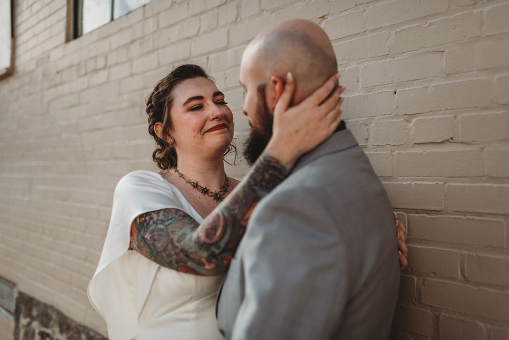Baltimore wedding photographers captures bride and groom embracing with bride holdin gthe back of the grooms head and smiling tenderly at him