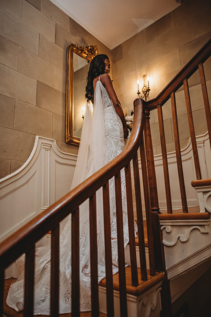 Baltimore photographers captures Belmont country club wedding with bride walking up wooden stairs while holding her wedding bouquet and looking over her shoulder