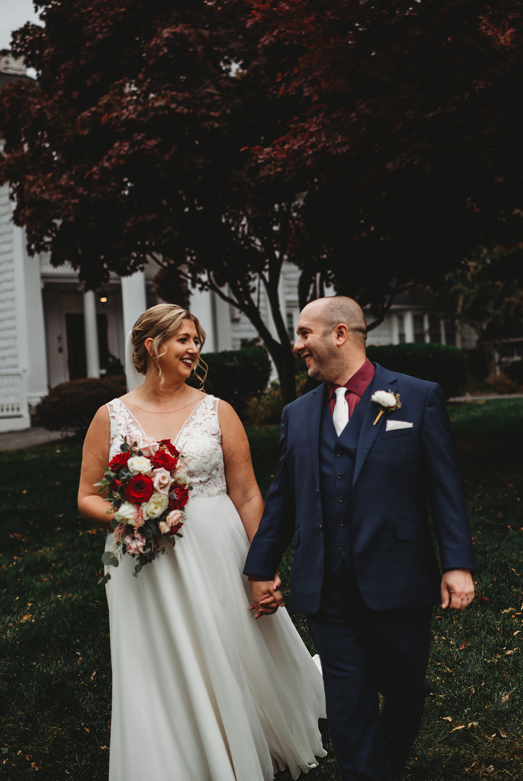 Baltimore wedding photographers captures bridal portraits of husband and wife holding hands and walking on the lawn of Overhills mansion for their wedding day