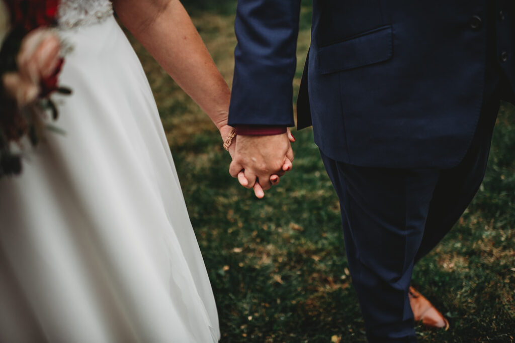 bride and groom holding hands while walking through their Baltimore wedding venue captured by Maryland wedding photographer