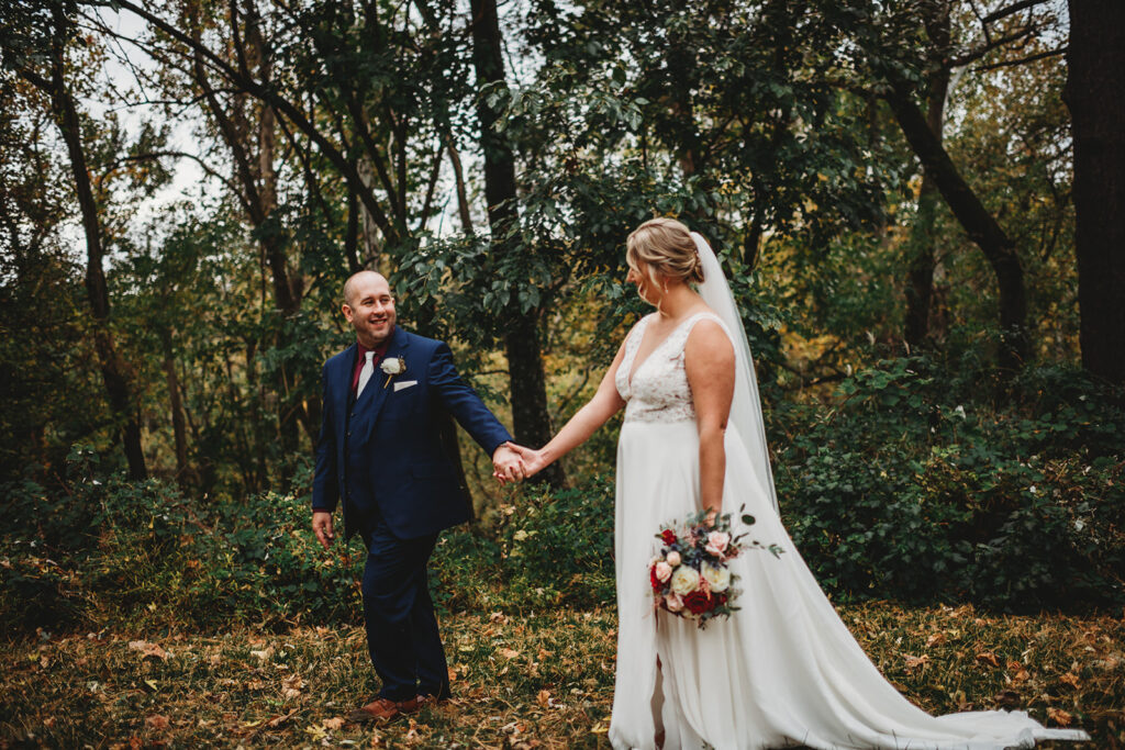 Maryland wedding photographer captures bridal photos with groom holding his brides hand and leading her through a garden 