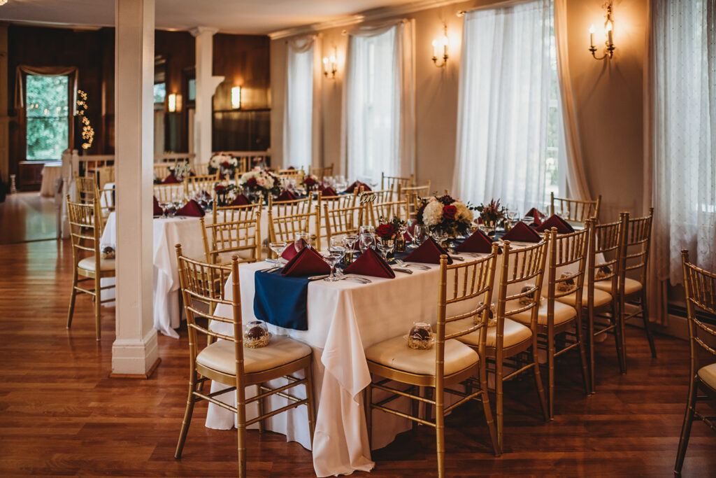 Maryland wedding photographer captures reception hall Decour with gold chairs and blue and red details inside of Overhills mansion wedding venue