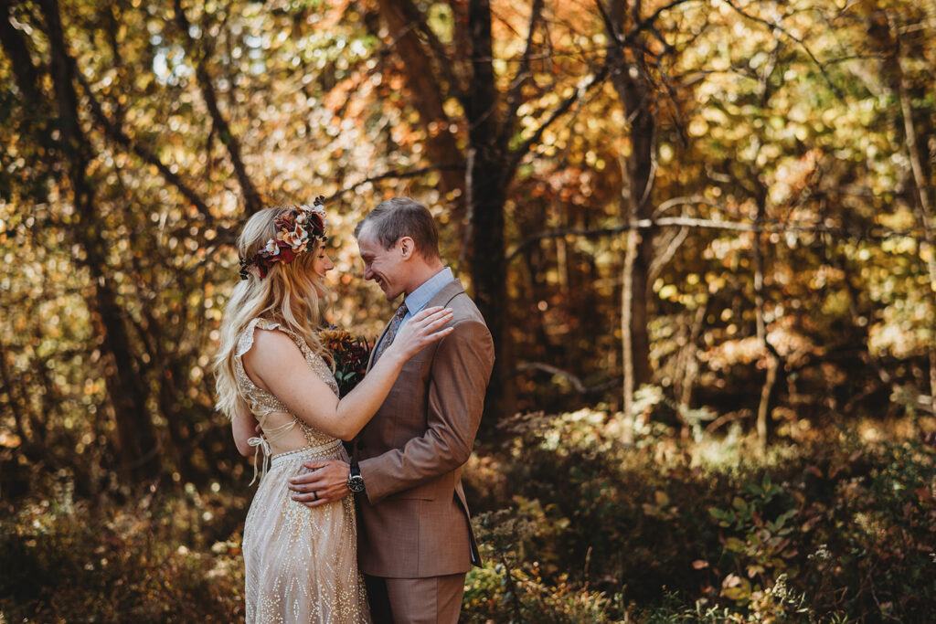 fall wedding in Baltimore with bride and groom holding each other and laughing in the woods for their fall wedding pictures with Baltimore photographers