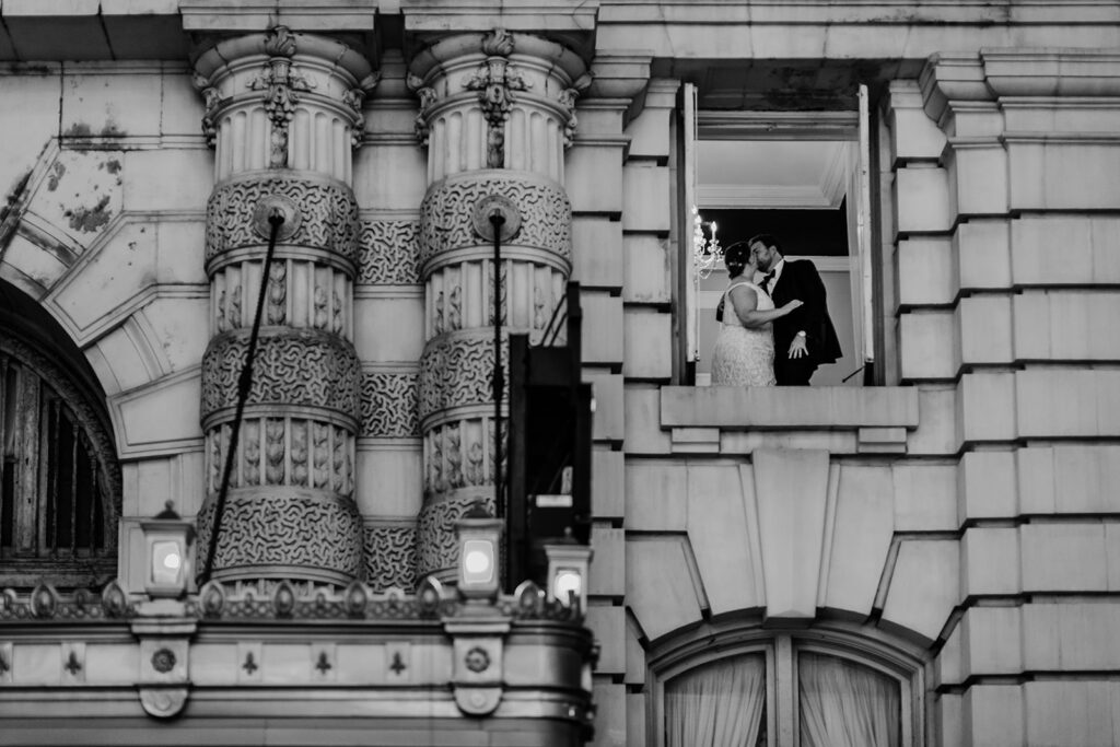 Baltimore photographers captures bride and groom kissing in a window in the second story of the Belvedere wedding venue