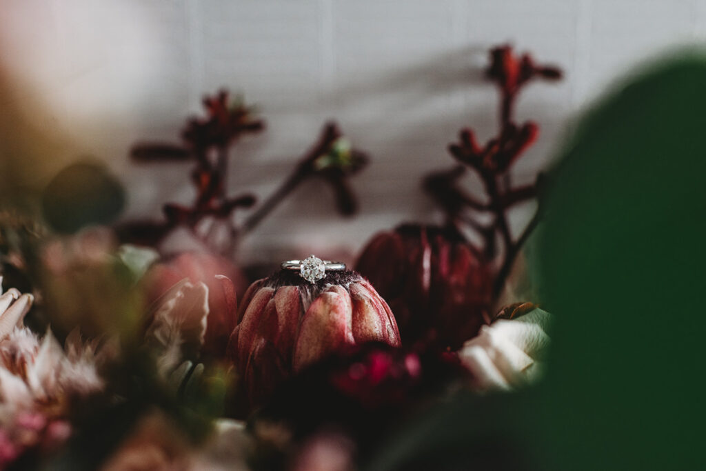Maryland wedding photographer captures detail shot of engagement ring sitting on a flower in the brides bouquet