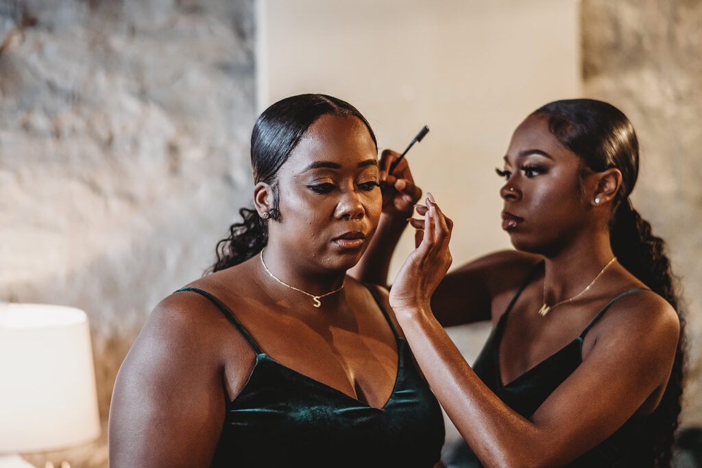 bridesmaids doing each others hair and make up in a bridal suite in a Baltimore wedding venue as they get ready captured by Baltimore wedding photographers