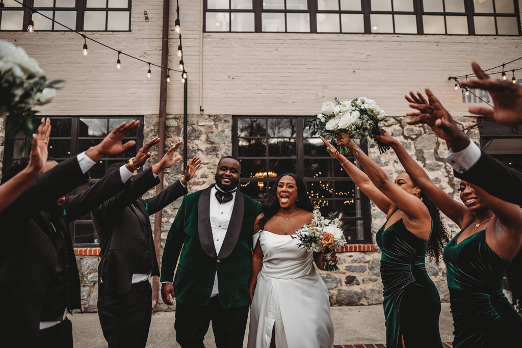 Maryland wedding photographer captures bride and groom walking through their bridal party as they all raise their arms in the air at a Baltimore wedding venue