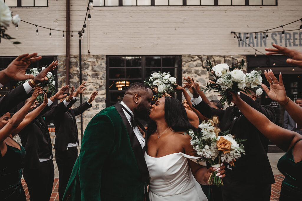 Baltimore wedding photographers capture bride and groom kissing while wedding party celebrates them