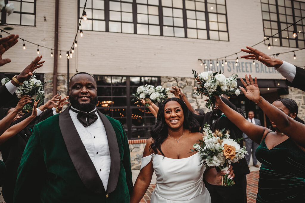 bride and groom holding hands and walking through their bridal party as they raise their hands over the couples head and cheers captured by Baltimore photographers 