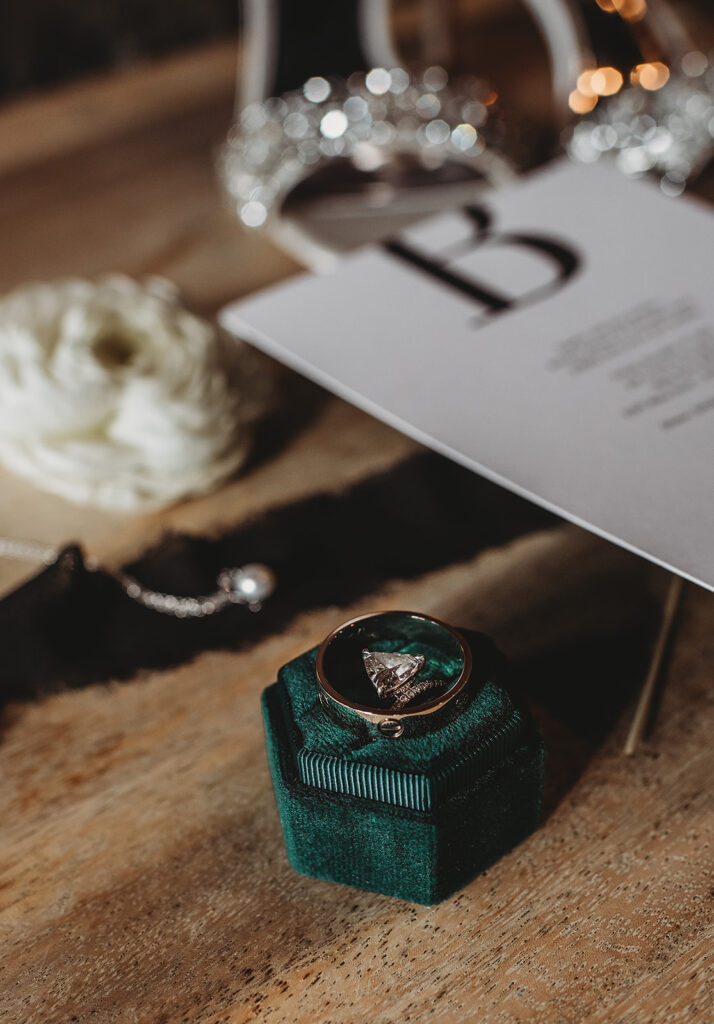 Maryland wedding photographer photographs engagement ring and wedding bands with the wedding invitation behind them
