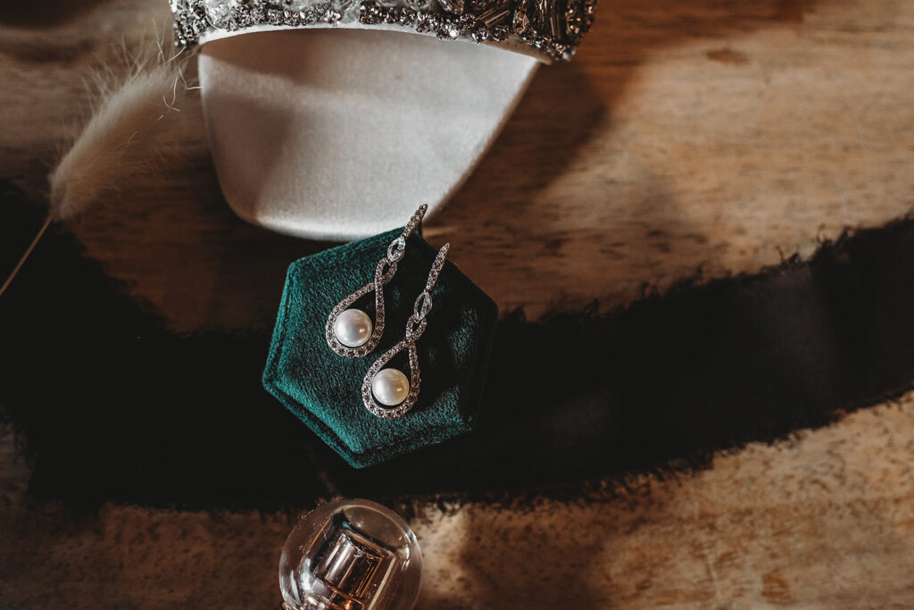 brides pearl and diamond earrings sitting on a green hexagon box on a wooden table captured by Maryland wedding photographer