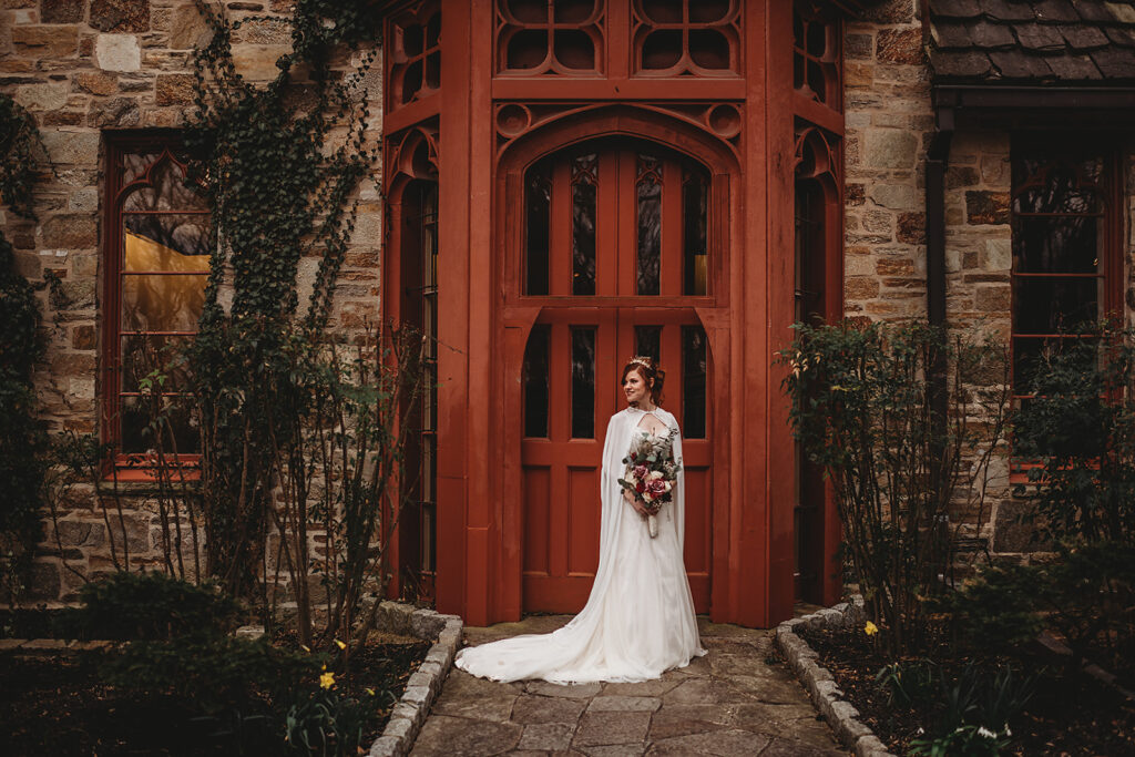 Baltimore wedding photographers capture bride standing outside red door in wedding dress