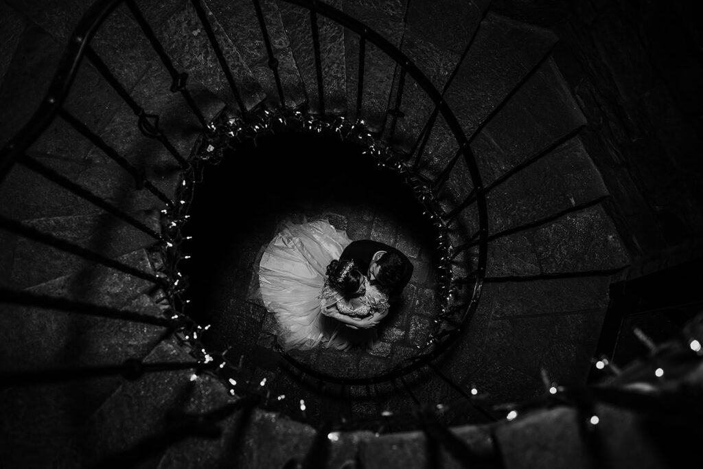 Baltimore wedding photographers captures unique wedding photography at Maryland wedding venue with bride and groom sitting together at the bottom of a spiral staircase