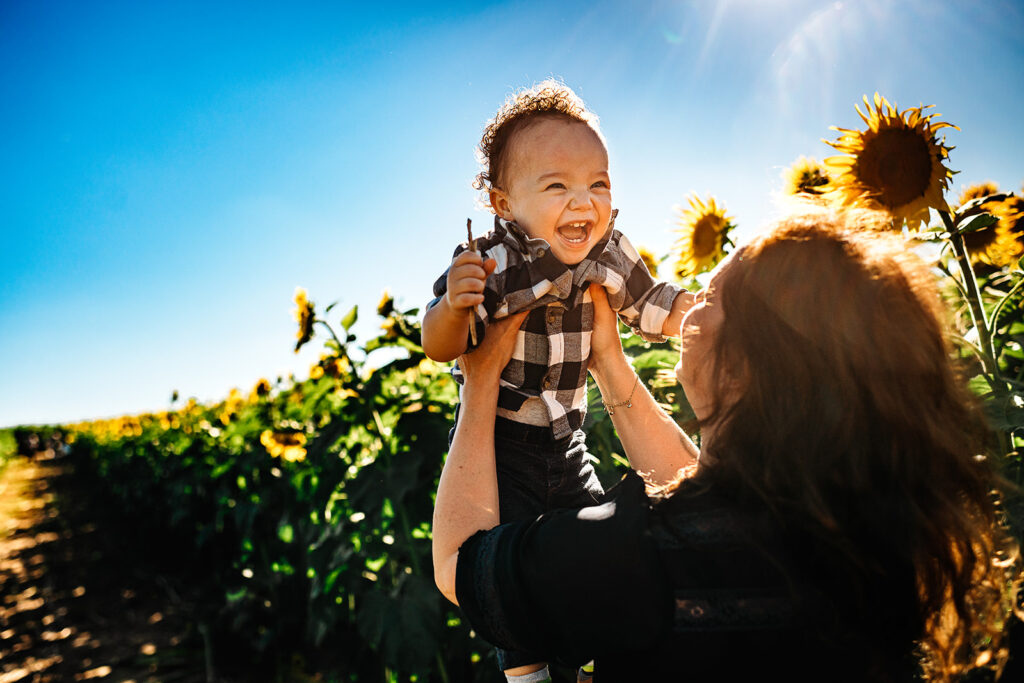 Baltimore photographers capture mother holding baby in the air during sunflower field photos