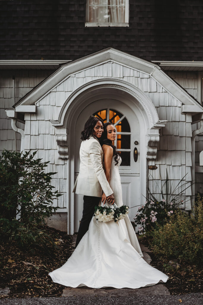 lgbtq wedding with lesbian couple posing in front of their white cottage Baltimore wedding venue captured by Baltimore photographers