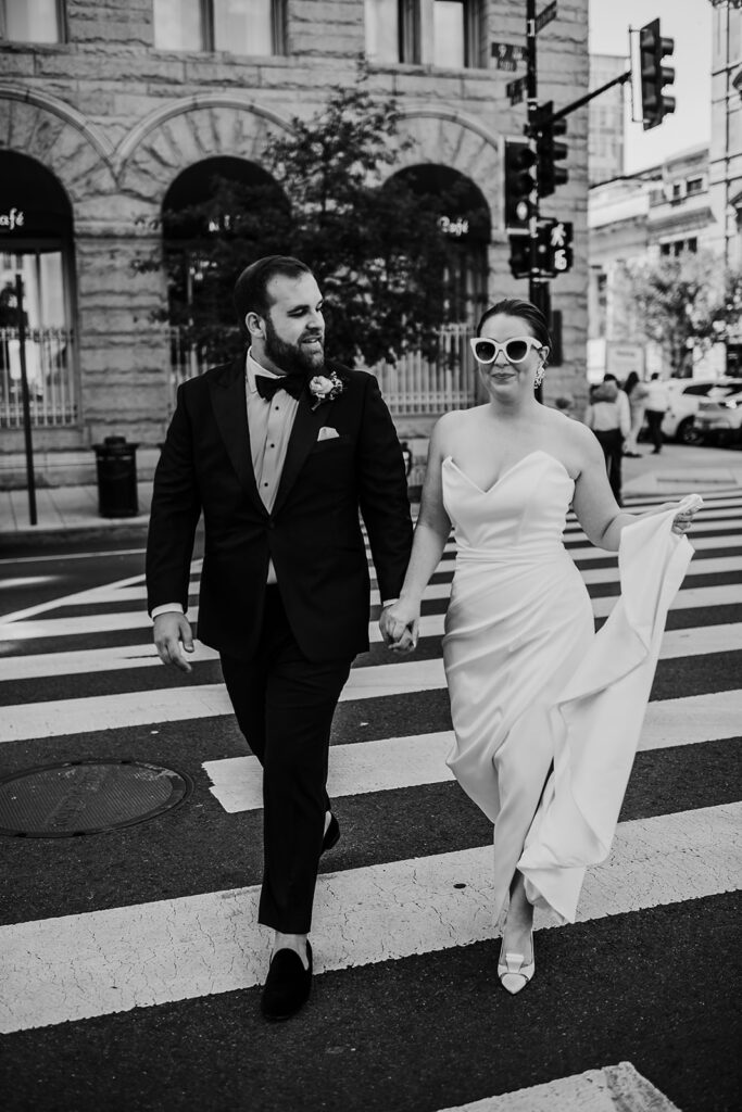 Baltimore wedding photographers capture black and white portrait of bride and groom walking across the street