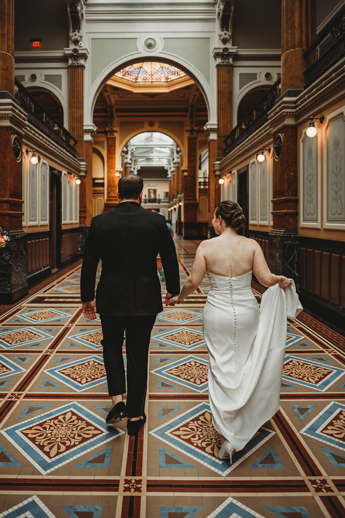 Baltimore wedding photographers capture bride and groom walking inside Riggs Hotel