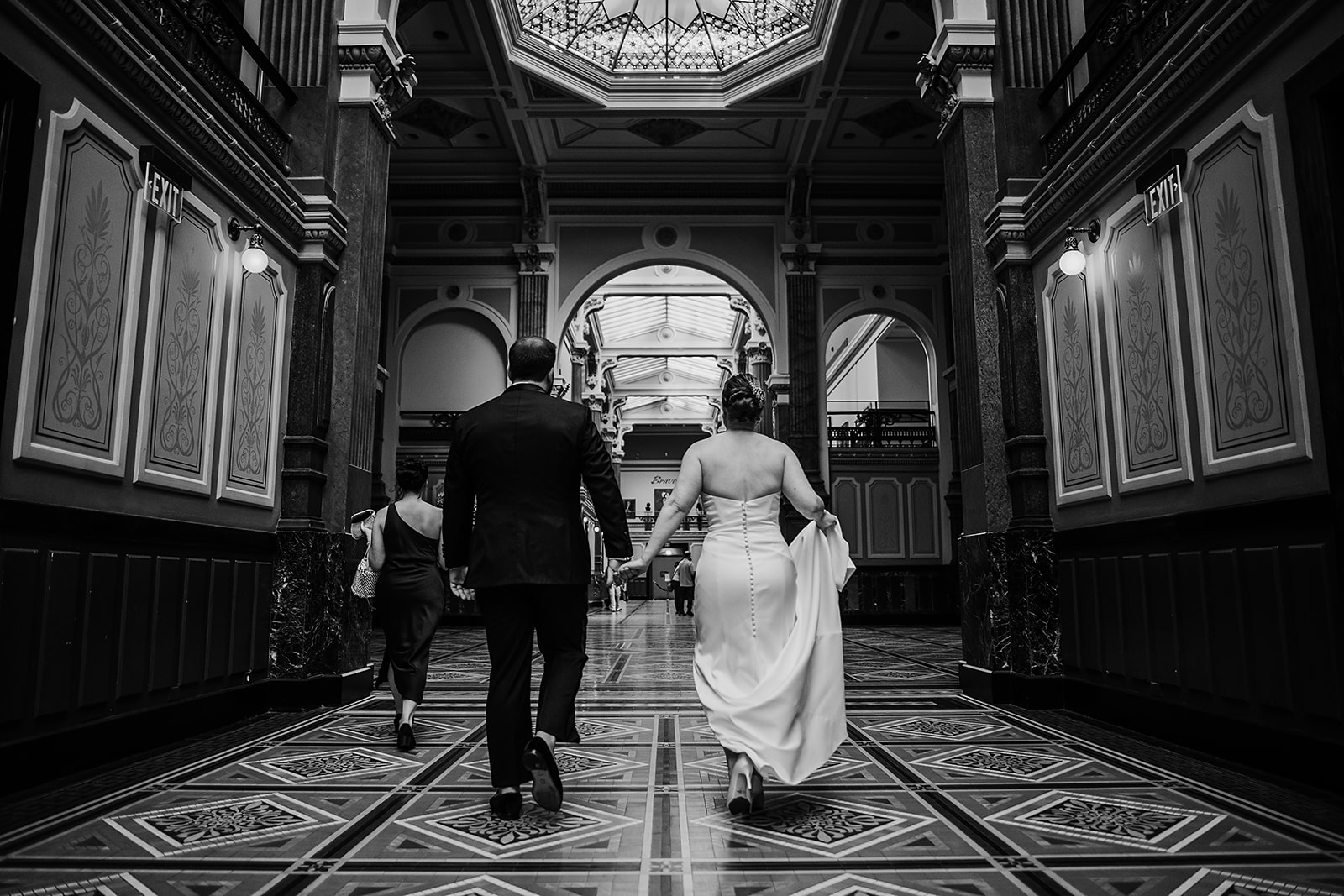 Maryland wedding photographer captures bride and groom holding hands and walk through the Riggs Hotel DC wedding