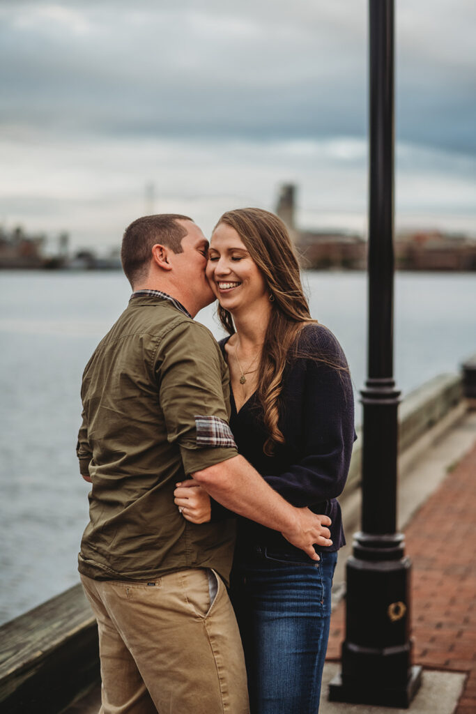 Baltimore wedding photographers capture man and woman kissing by the  water at Fells Point