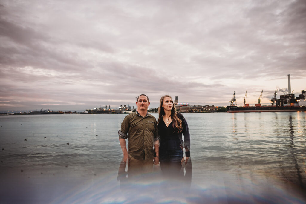Baltimore wedding photographers capture couple in the water standing together during Fells Point engagement photos