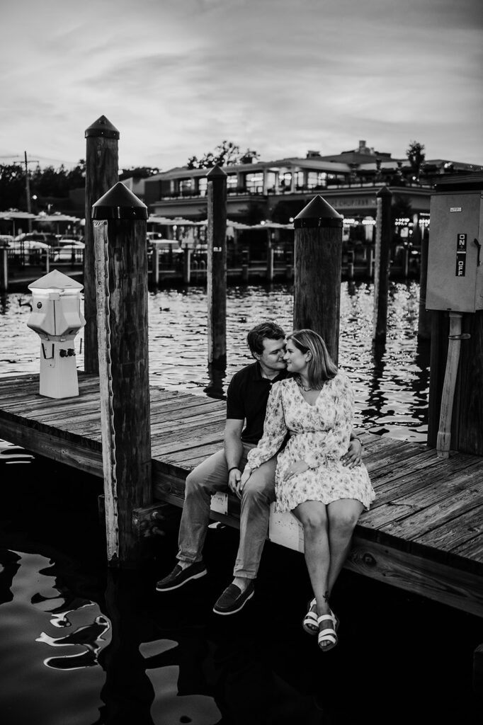 Baltimore wedding photographers capture black and white portrait of couple sitting on dock