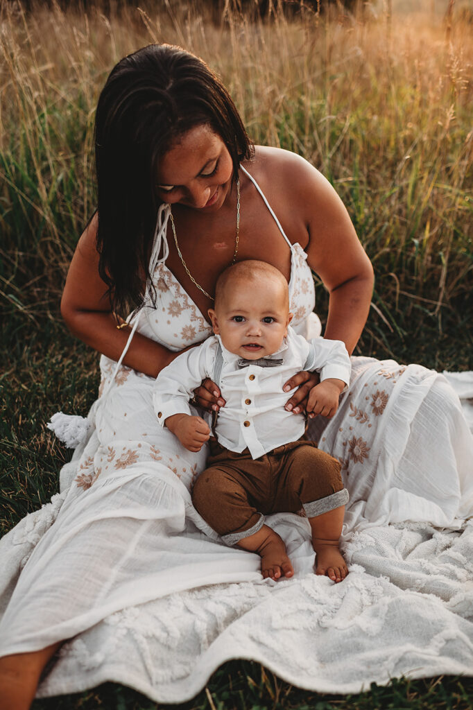 Baltimore photographer captures mother holding baby while sitting in field wearing white dress