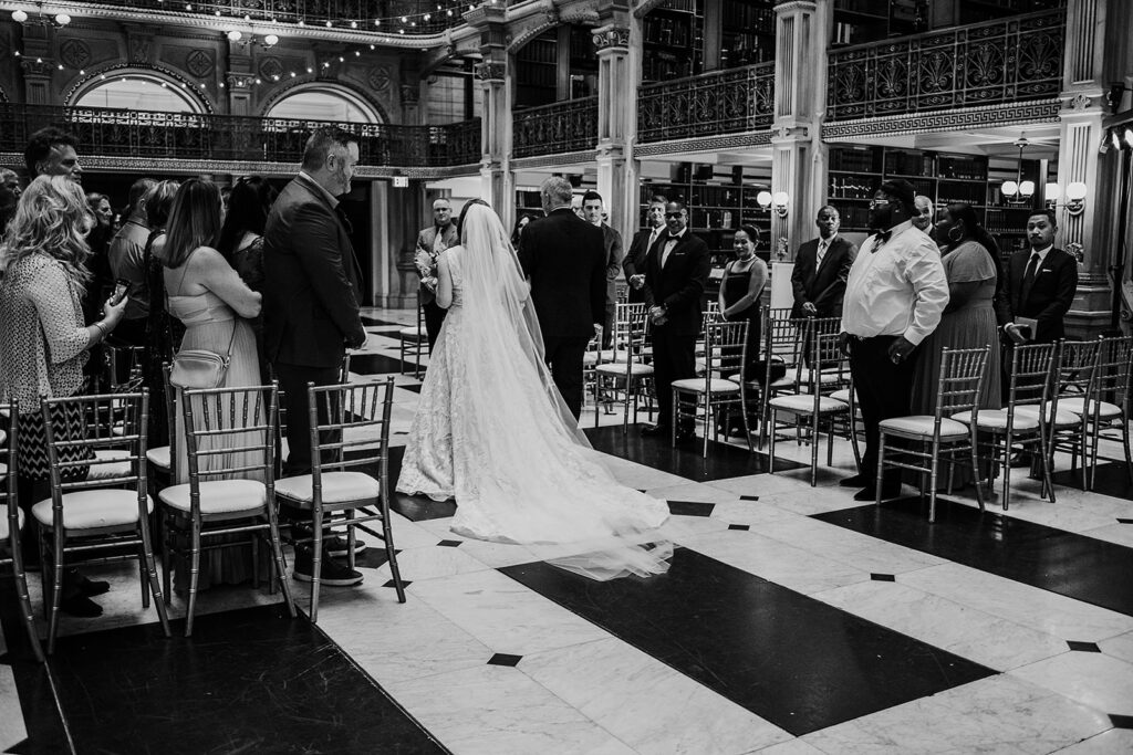 Baltimore wedding photographer captures black and white portrait of bride walking down aisle