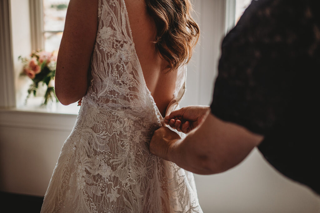 Baltimore wedding photographers capture bride getting zipped into wedding dress