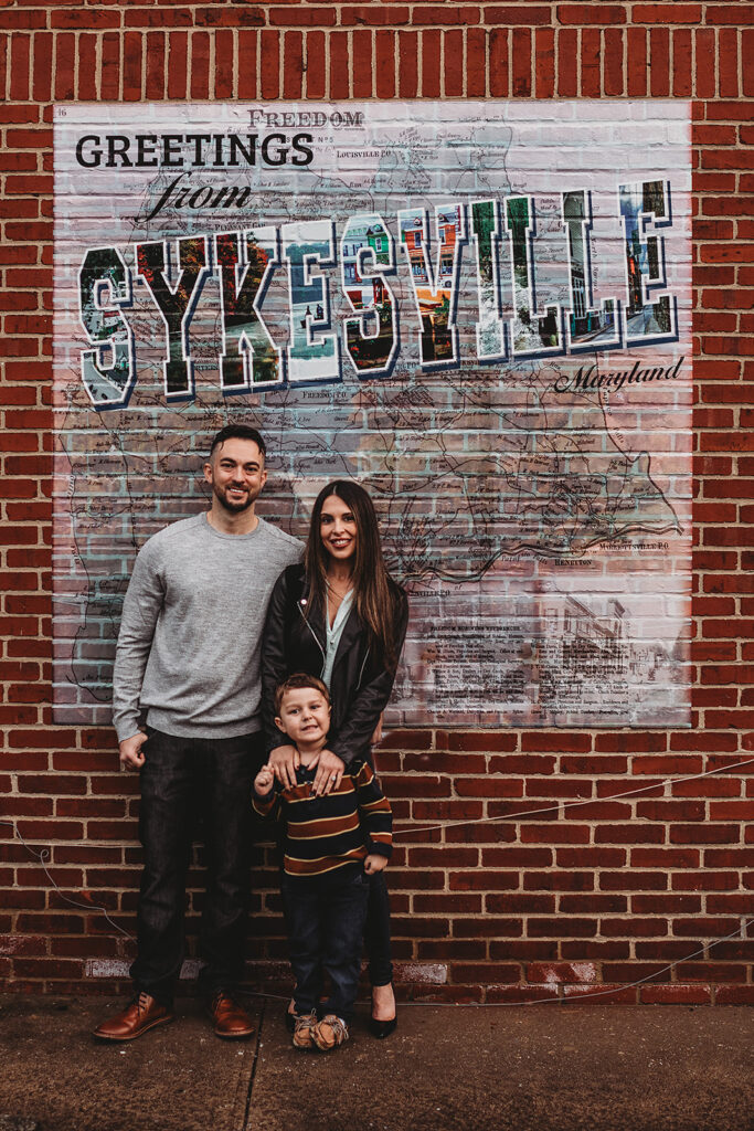 Baltimore photographers capture couple standing together with son against mural