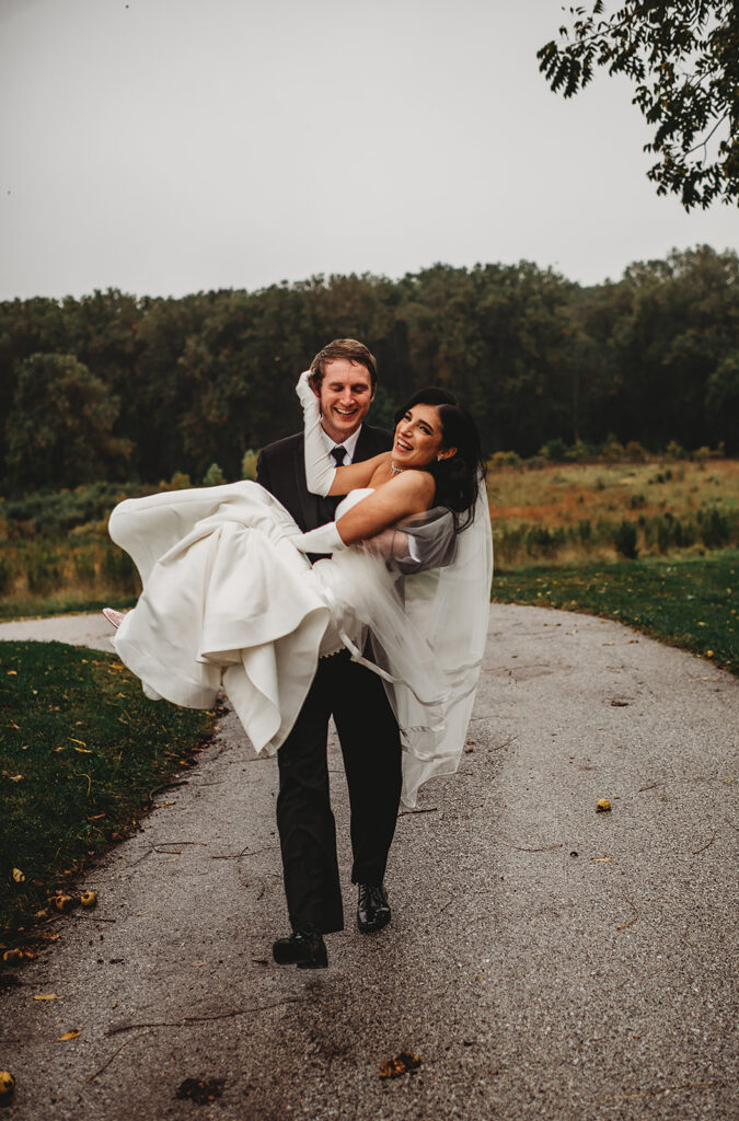 Baltimore wedding photographer captures groom carrying bride after Baltimore wedding