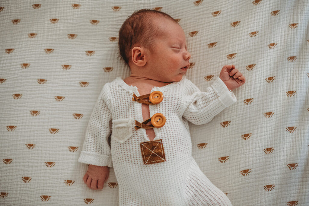 Baltimore photographers capture newborn laying in bed wearing white outfit