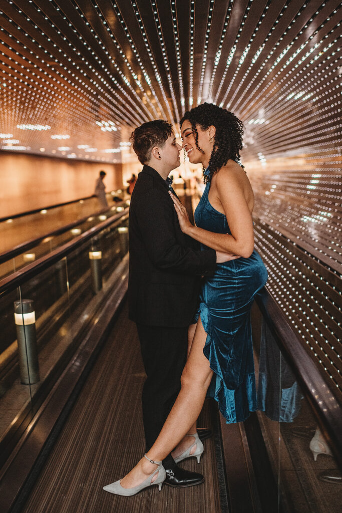 Maryland engagement photographer captures woman sitting on rail as fiance leans into kiss her