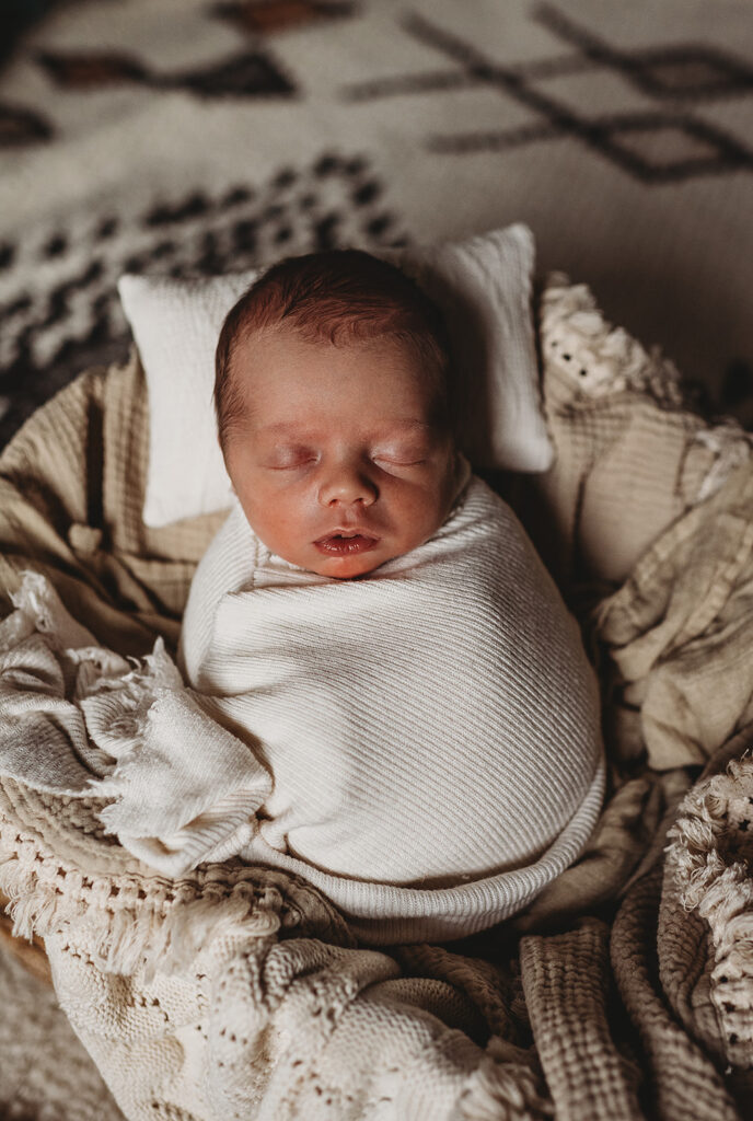 Baltimore photographers capture newborn swaddled in cream swaddle during newborn photos at home