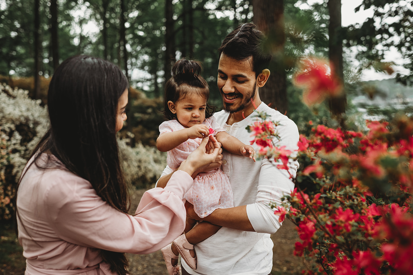 Maryland family photos with father holding toddler daughter as the mother shows the child flowers
