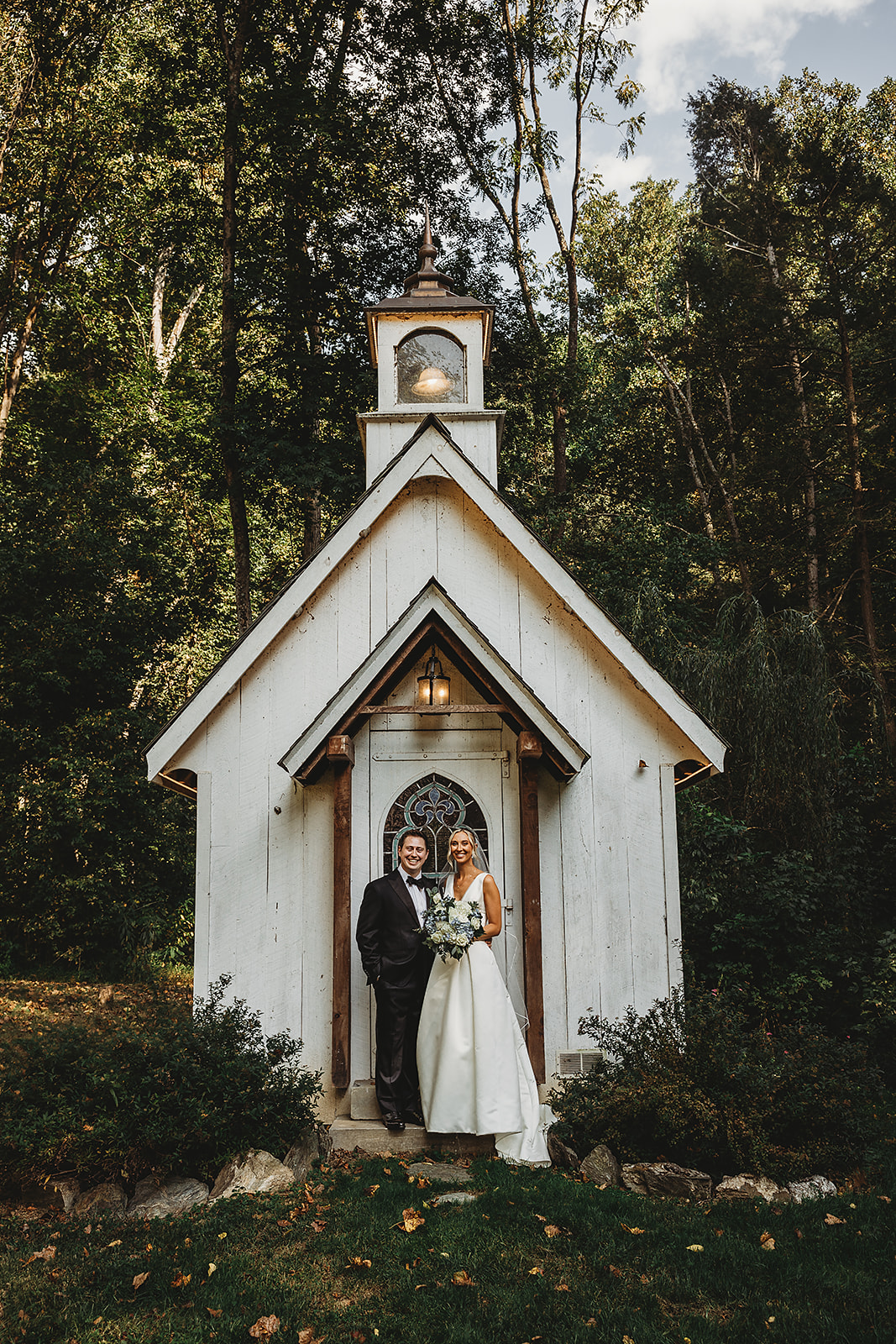 white chapel with bride and groom standing in front of it for wedding portraits at Drumore Mill